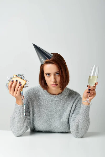 Jeune femme en chapeau de fête tenant sandwich avec mousseline et verre de champagne, célébration du Nouvel An — Photo de stock