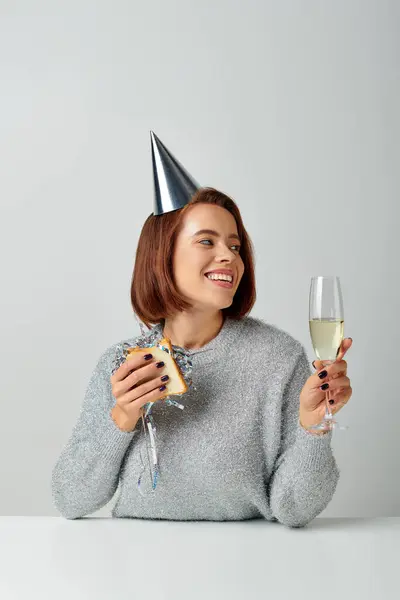 Femme heureuse dans le chapeau de fête tenant sandwich avec tinsel et verre de champagne, célébration du Nouvel An — Photo de stock