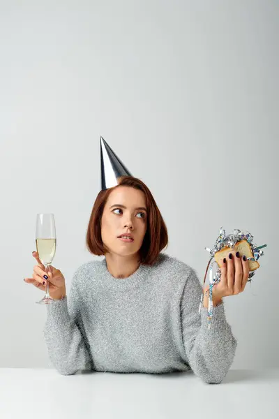 Jeune femme dans le chapeau de fête tenant verre de champagne et sandwich avec tinsel, Joyeux Noël concept — Photo de stock