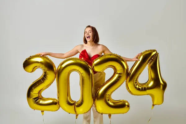 Happy New Year, excited young woman in trendy attire holding balloons with 2024 numbers on grey — Stock Photo