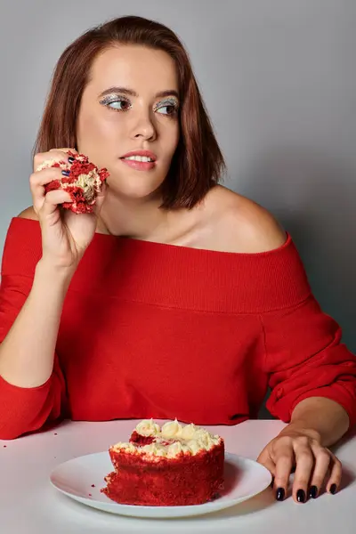 Mulher atraente em traje vermelho segurando pedaço de bolo de bento no fundo cinza, feliz aniversário — Fotografia de Stock
