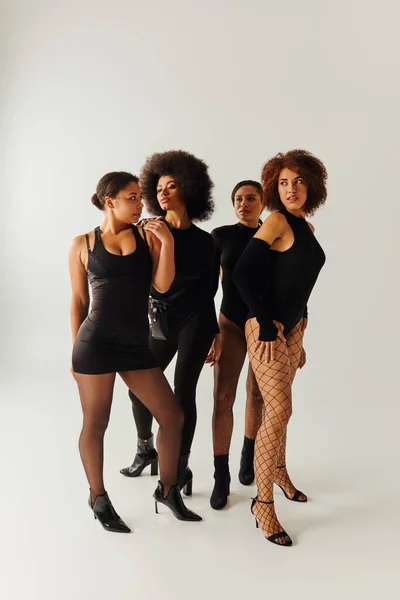Quattro donne afroamericane accattivanti in nero seducente abbigliamento posa insieme, concetto di moda — Foto stock