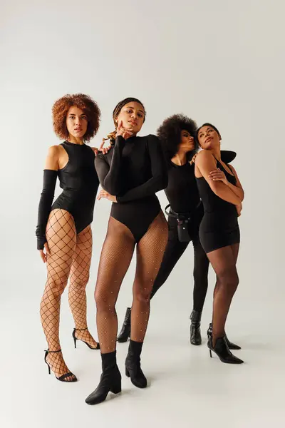 Vier attraktive afrikanisch-amerikanische Frauen in schwarzer verführerischer Kleidung posieren zusammen, Modekonzept — Stockfoto
