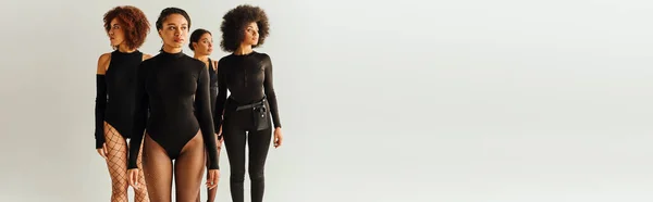 Attractive young african american female friends in black appealing bodysuits, fashion, banner — Stock Photo