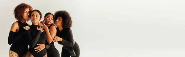 Séduisantes femmes africaines américaines sexy en costumes élégants noirs posant ensemble, mode, bannière — Photo de stock