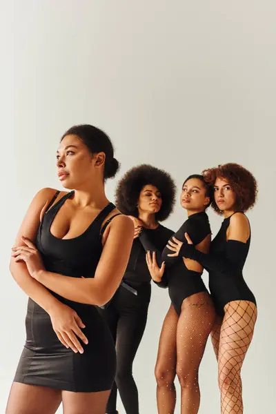 Atractivo sexy africano americano mujeres en negro elegante bodysuits posando juntos, concepto de moda - foto de stock