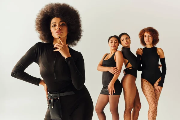 Atractivo sexy africano americano mujeres en negro elegante bodysuits posando juntos, concepto de moda - foto de stock