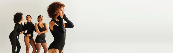 Ansprechende sexy afrikanisch-amerikanische Frauen in schwarzen stylischen Bodys posieren zusammen, Mode, Banner — Stockfoto