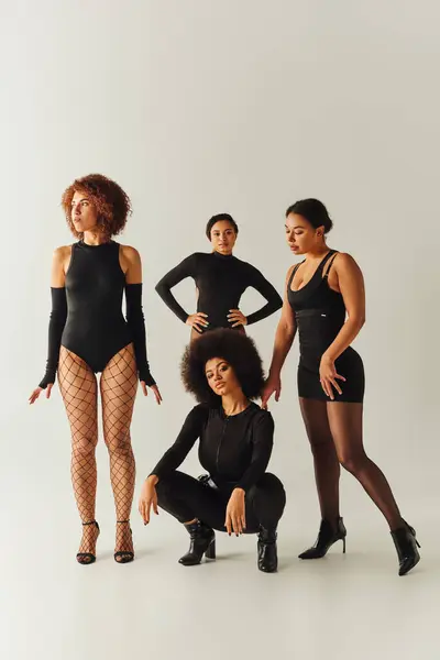 Hermosas amigas afroamericanas posando juntas en trajes negros sexy, concepto de moda - foto de stock