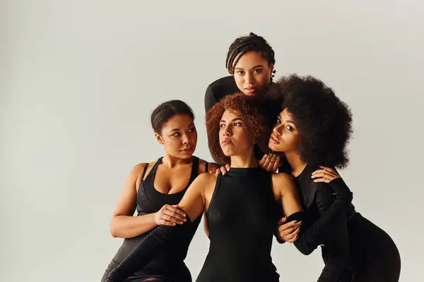 Mujeres afroamericanas atractivas en trajes atractivos negros posando en cubo negro, concepto de moda - foto de stock