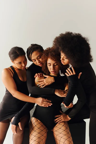 Attraktive afrikanisch-amerikanische Frauen in schwarzen verführerischen Kleidern posieren auf schwarzem Würfel, Modekonzept — Stockfoto