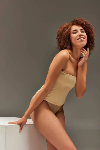 Gioiosa africana americana modello femminile in biancheria intima posa felicemente su sfondo grigio, concetto di moda — Foto stock