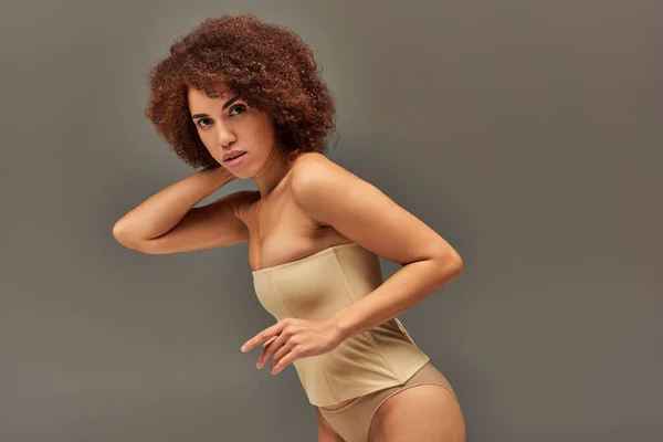 Modelo femenino afroamericano atractivo en ropa interior pastel posando sobre fondo gris, concepto de moda - foto de stock