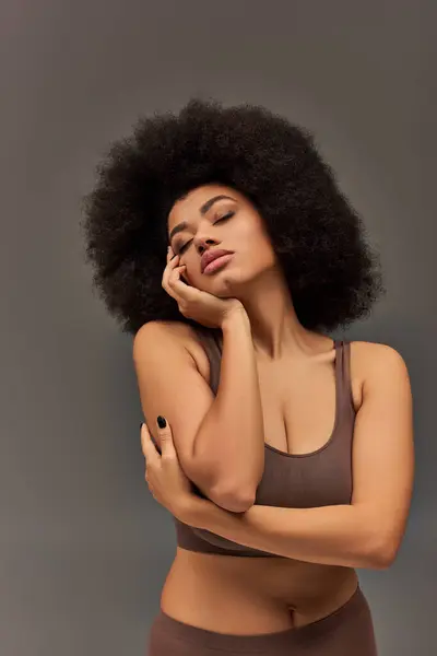Mujer afroamericana joven en ropa interior pastel con esmalte de uñas negro posando seductoramente, moda - foto de stock