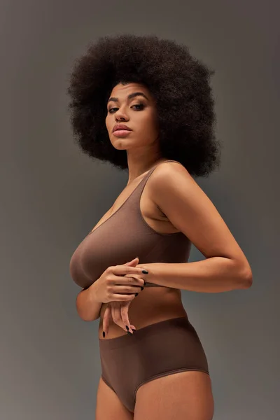 Jovem mulher afro-americana em roupa interior pastel com esmalte preto posando de forma fascinante, moda — Fotografia de Stock