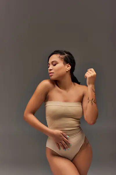 Jovem mulher americana africana atraente em roupa interior pastel bege posando a sério, conceito de moda — Fotografia de Stock