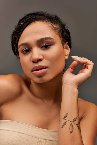 Giovane donna afroamericana attraente in biancheria intima beige pastello posa sul serio, concetto di moda — Foto stock