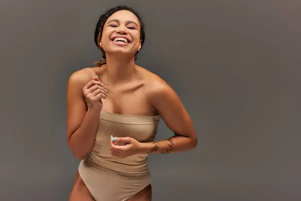 Радостная африканская американская модель в бежевом пастельном нижнем белье с большим временем, концепция моды — стоковое фото