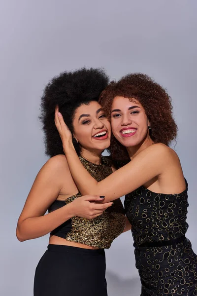 Duas mulheres afro-americanas bastante felizes em trajes festivos festejando juntas, conceito de moda — Fotografia de Stock
