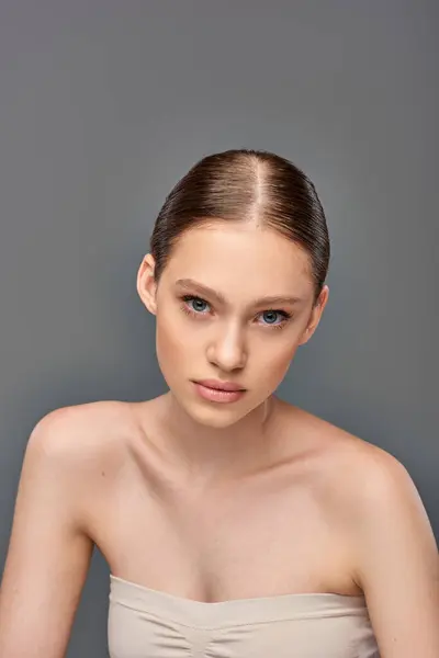 Portrait of beautiful young woman with perfect skin looking at camera on grey background, youth — Stock Photo