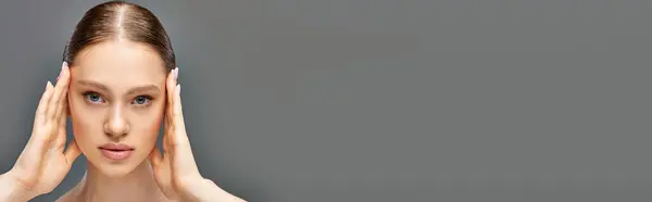 Ritratto di giovane donna con pelle perfetta posa con le mani vicino al viso su sfondo grigio, banner — Foto stock