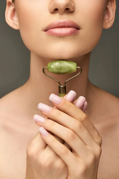 Recadrée jeune femme faisant massage du cou avec rouleau de jade vert sur fond gris, auto-soin — Photo de stock