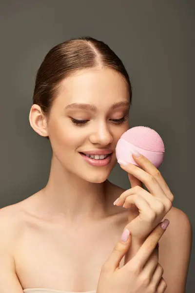 Fröhliche Frau mit Reinigungsbürste auf grauem Hintergrund, Beauty-Gadget und Hautpflegekonzept — Stockfoto