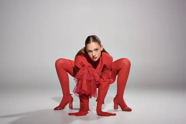Glamouröses junges Model in roter Kleidung mit High Heels und hellen Strumpfhosen posiert auf grauem Hintergrund — Stockfoto