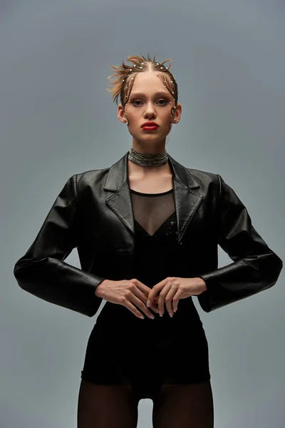 Стильная женщина с жемчугом в волосах позирует в кожаной куртке и черные колготки на сером фоне — стоковое фото