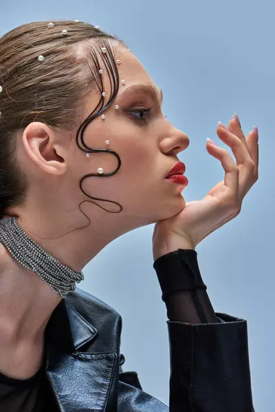 Seitenansicht des hübschen jungen Models mit trendigen Perlstiften im Haar und roten Lippen, die vor grauem Hintergrund posieren — Stockfoto