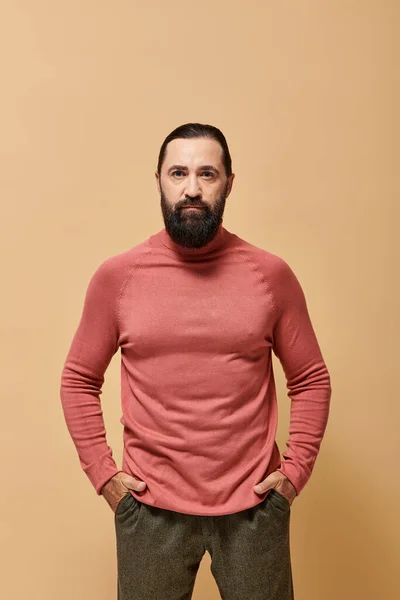 Portrait, handsome focused man with beard posing in pink turtleneck jumper  on beige background — Stock Photo