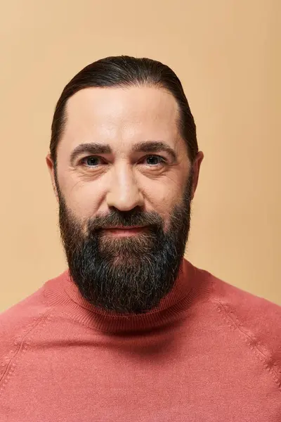 Portrait of handsome man with beard posing in pink turtleneck jumper on beige background — Stock Photo