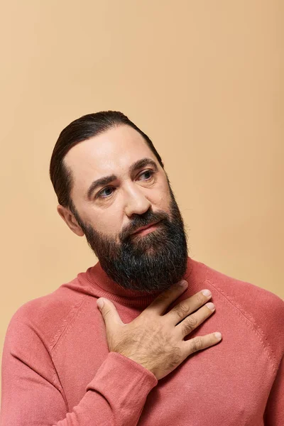 Porträt, ernster und gutaussehender Mann mit Bart posiert im Rollkragenpullover auf beigem Hintergrund — Stockfoto