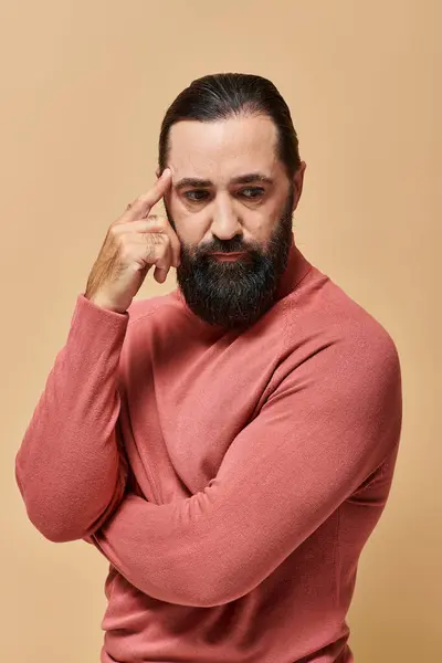 Porträt, ernster und gutaussehender Mann posiert in rosa Rollkragenpullover auf beigem Hintergrund, Bart — Stockfoto