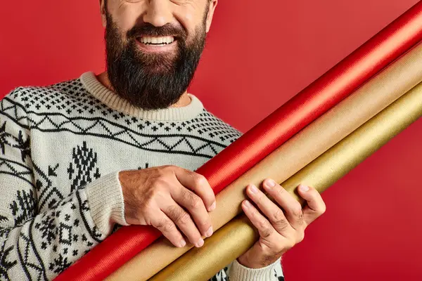 Homme barbu heureux cultivé en chandail d'hiver tenant papier cadeau sur fond rouge, Joyeux Noël — Photo de stock