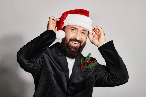 Портрет веселого красивого чоловіка в елегантному костюмі в капелюсі Санта на сірому фоні, Різдво — стокове фото