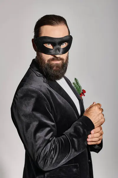 Christmas Masquerade ball, handsome bearded man in carnival mask and elegant suit on grey backdrop — Stock Photo