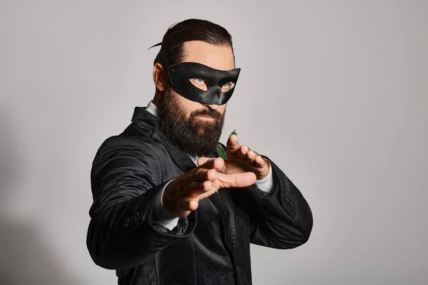 Christmas Masquerade ball, handsome bearded man in carnival mask and elegant suit on grey backdrop — Stock Photo