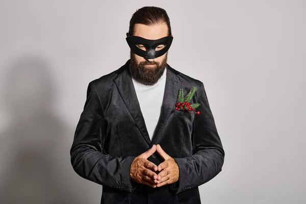 Masquerade ball, concentrated bearded man in carnival mask and elegant formal wear on grey backdrop — Stock Photo