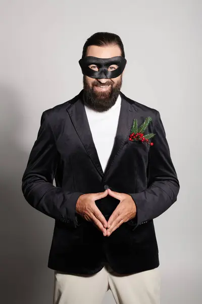 Masquerade ball, cheerful bearded man in carnival mask and elegant formal wear on grey backdrop — Stock Photo