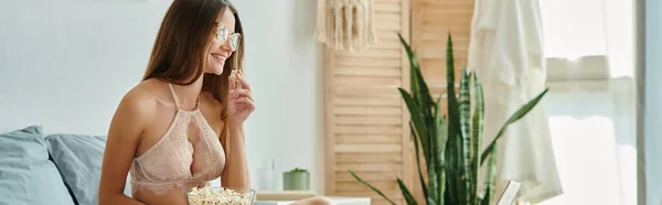 Весела приваблива жінка в сексуальній білизні в окулярах і довге волосся, насолоджуючись свіжим попкорном, банер — стокове фото