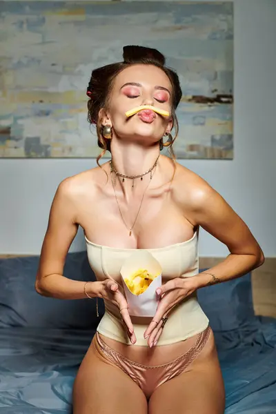 Sedutor mulher bonita com encrespadores de cabelo e acessórios em espartilho posando em movimento com batatas fritas — Fotografia de Stock