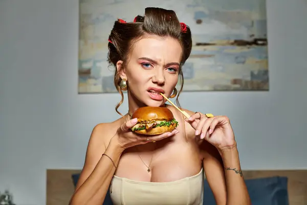 Jovem mulher emocional em espartilho sexy bege segurando enorme hambúrguer delicioso e olhando para a câmera — Fotografia de Stock