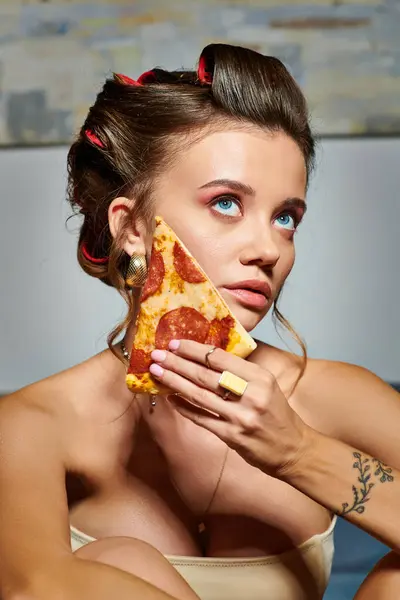 Hermosa joven con rizadores de pelo y accesorios posando con rebanada de deliciosa pizza - foto de stock