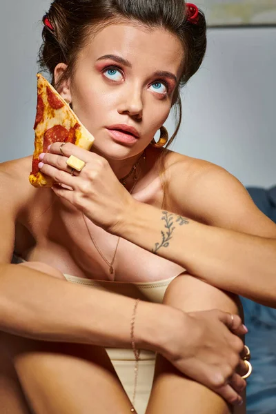 Attraente donna sexy con bigodini capelli in corsetto seducente in posa con fetta di deliziosa pizza — Foto stock