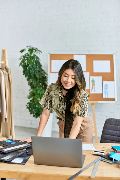 Happy asian personal stylist working near laptop and color samples in own fashion atelier, business — Stock Photo