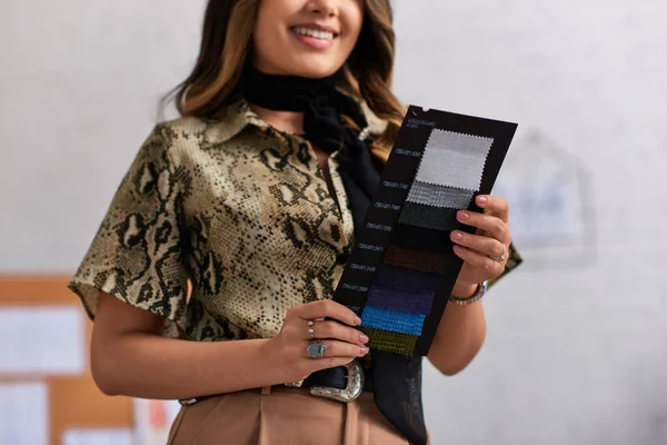 Cropped view of smiling and stylish designer holding color samples in private clothes atelier — Stock Photo