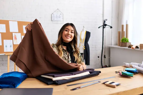 Delighted asian designer with quality fabric sample looking at camera in modern personal atelier — Stock Photo