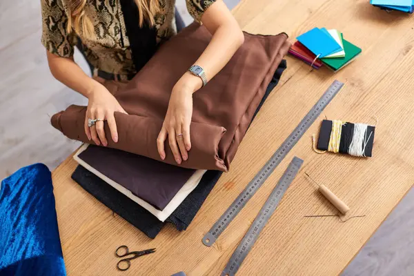 Vista cortada de roupas estilista verificando amostras de tecidos perto de suprimentos de costura no atelier de moda — Fotografia de Stock