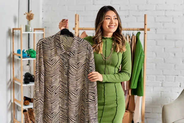 Alegre asiático personal estilista con moda a medida animal impresión blusa mirando lejos en atelier - foto de stock